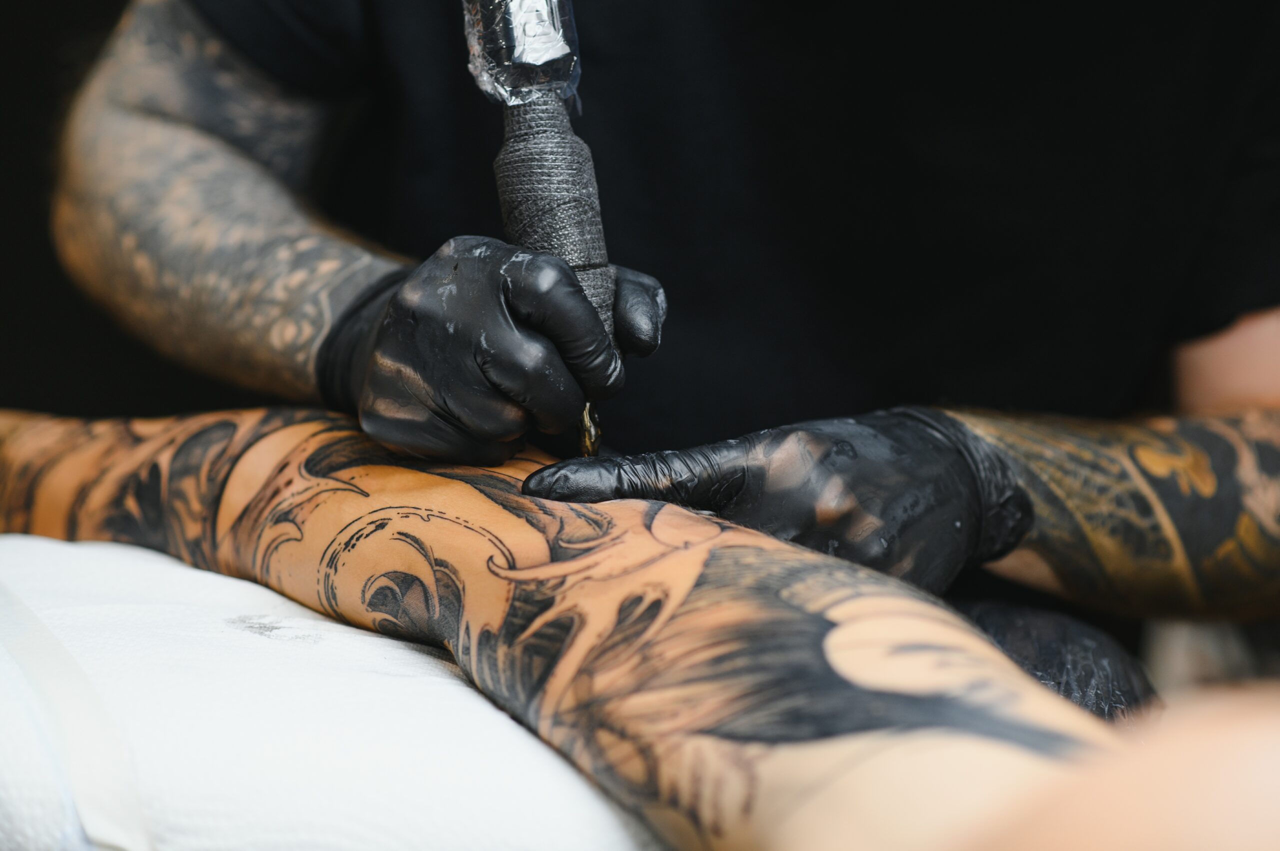Tattoo salon. The tattoo master is tattooing a man. Tattoo machine, safety and hygiene at work. Close-up, tinted, tattooist.